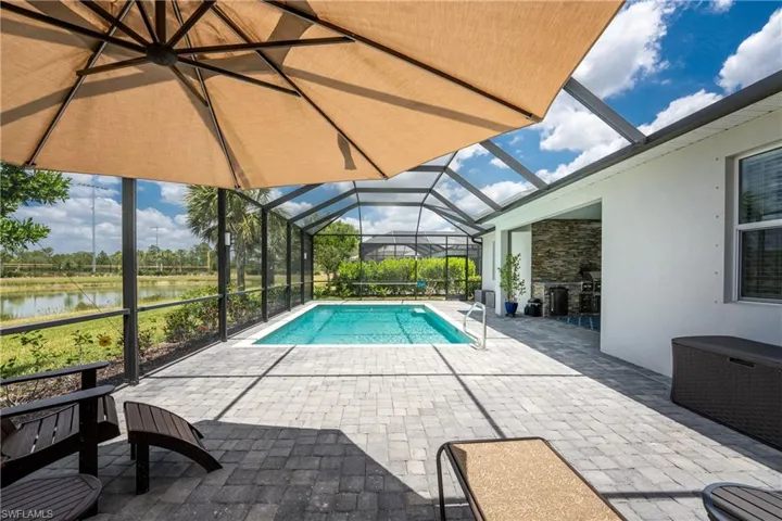 Pool with glass enclosure, a water view, and a patio area