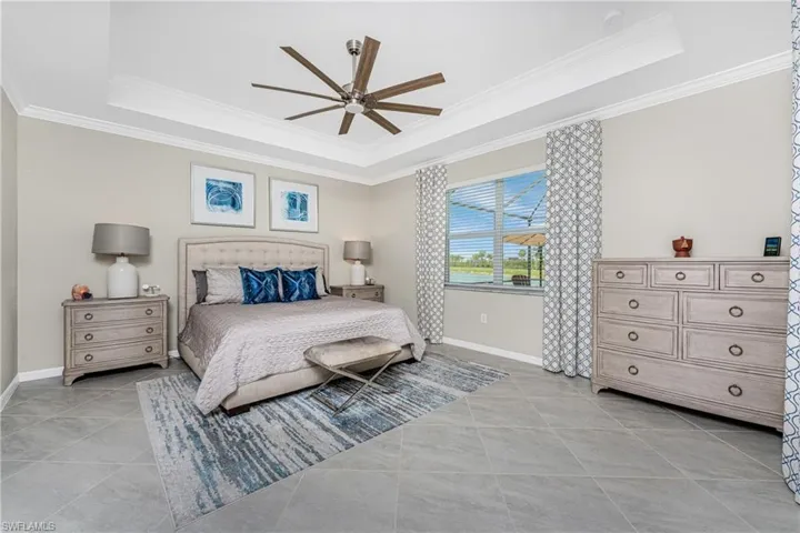 Bedroom featuring crown molding, a tray ceiling, baseboards, and light tile patterned floors