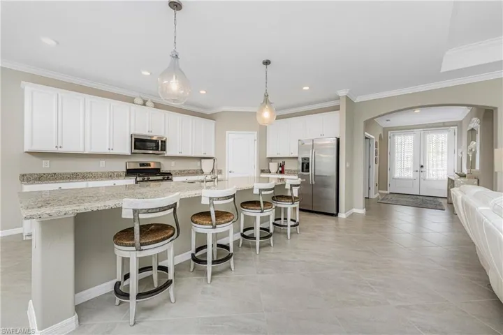 Kitchen featuring a sink, recessed lighting, a large island with sink, arched walkways, and stainless steel appliances