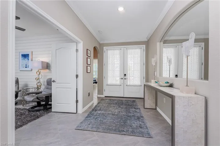 Entryway with arched walkways, ornamental molding, french doors, and a healthy amount of sunlight