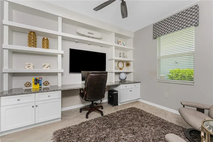 Office space with built in study area, a ceiling fan, baseboards, and light tile patterned flooring