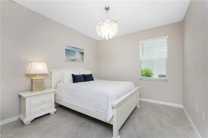 Bedroom with baseboards, light tile patterned floors, and a notable chandelier