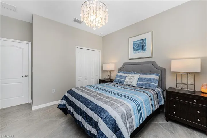 Tiled bedroom featuring a notable chandelier, visible vents, baseboards, and a closet