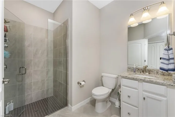 Bathroom featuring a shower stall, vanity, baseboards, tile patterned floors, and toilet