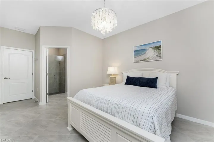 Bedroom featuring baseboards, connected bathroom, a notable chandelier, and visible vents