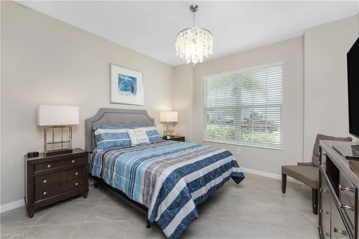 Bedroom with baseboards, light tile patterned flooring, and a notable chandelier