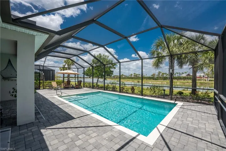 Outdoor pool with a water view, a lanai, and a patio area