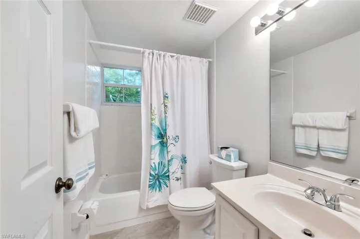 Full bath featuring shower / tub combo with curtain, vanity, and light tile patterned flooring