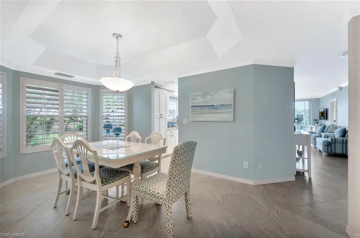 Dining room featuring a tray ceiling, ornamental molding, and tile patterned floors