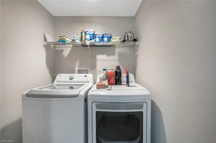 Laundry room with a textured wall and independent washer and dryer