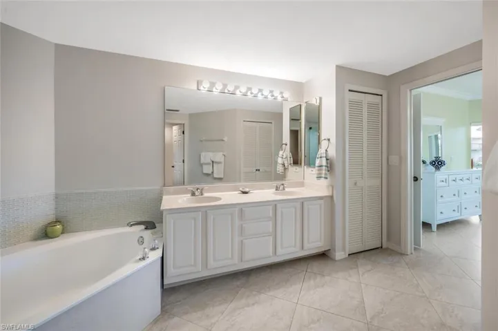 Bathroom featuring a closet, double vanity, and a bath
