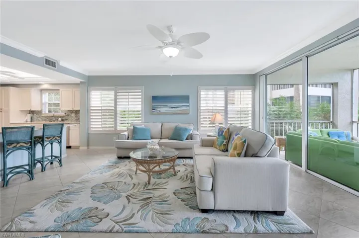 Living room with ceiling fan, crown molding, and light tile patterned floors