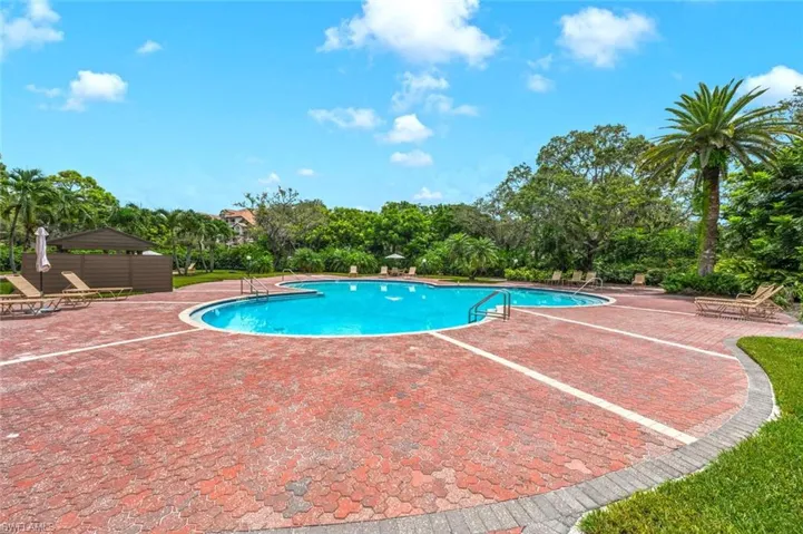 Community pool with a patio area and view of scattered trees