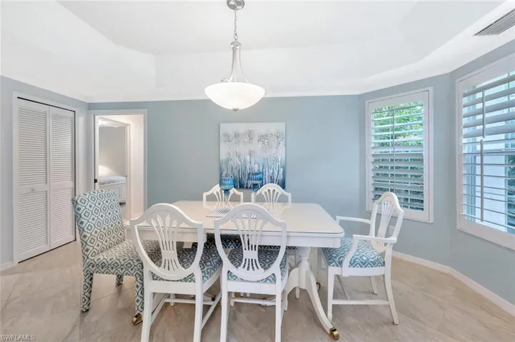 Dining space with a raised ceiling, crown molding, and light tile patterned floors