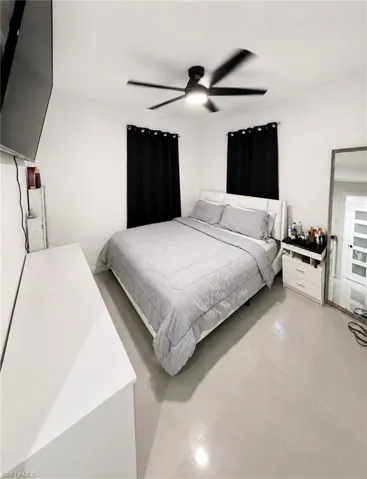White walls, light-toned tile flooring, and a modern ceiling fan