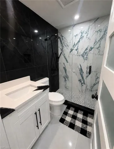White shaker vanity with black hardware, white rectangular sink, and black countertop