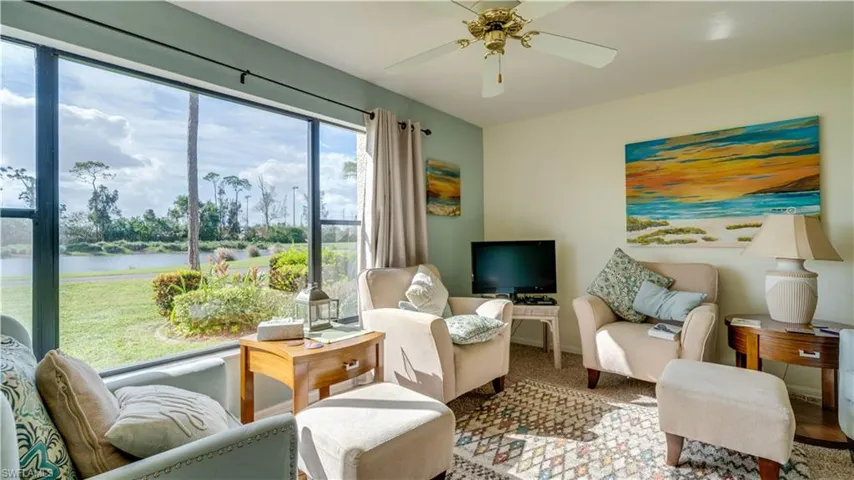 Living area with a water view, ceiling fan, and carpet flooring