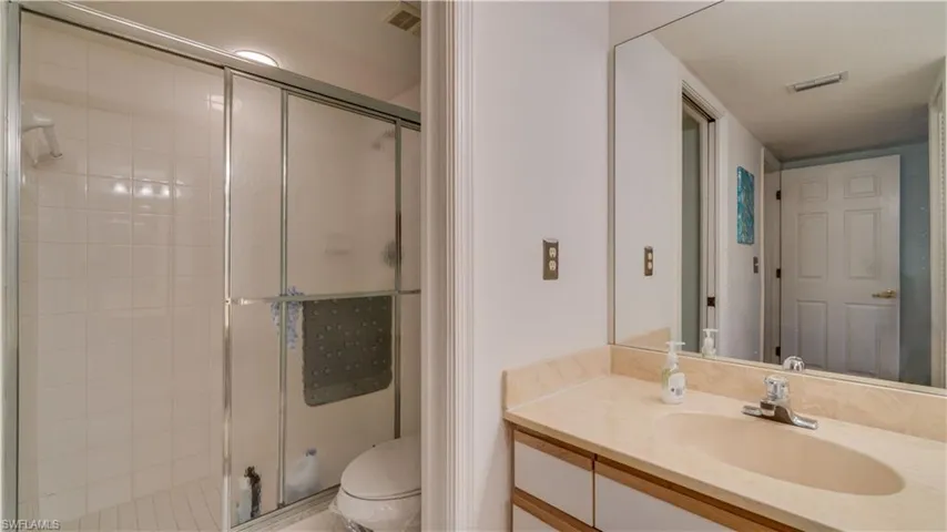 Bathroom with vanity, a shower with shower door, and toilet