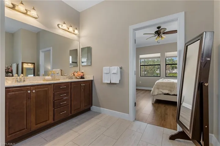 Bathroom with double vanity, ensuite bath, wood finish floors, ornamental molding, and a ceiling fan