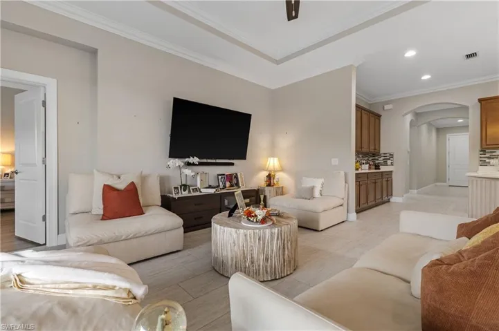 Living area with recessed lighting, ornamental molding, and arched walkways