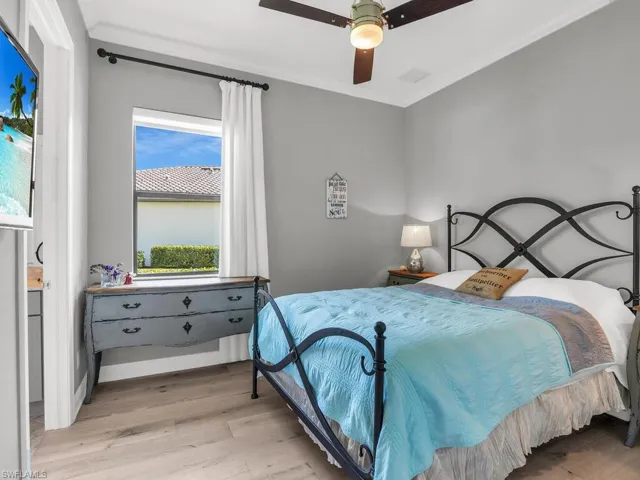 Bedroom featuring light hardwood / wood-style floors, crown molding, and ceiling fan