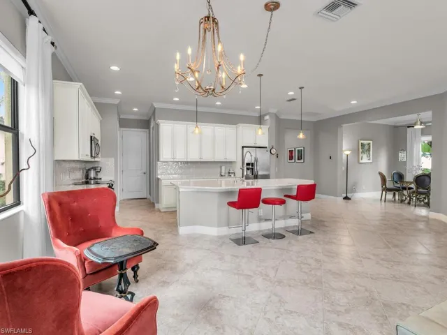 Kitchen with decorative light fixtures, white cabinetry, stainless steel appliances, decorative backsplash, and an island with sink