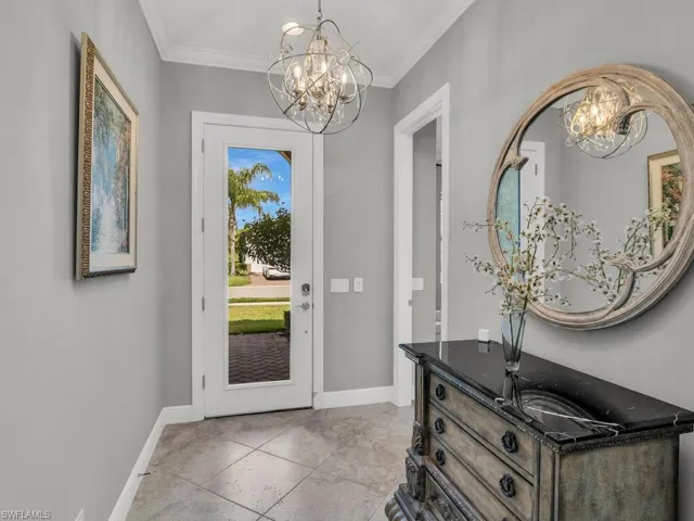 Foyer featuring a notable chandelier, crown molding, and light tile floors