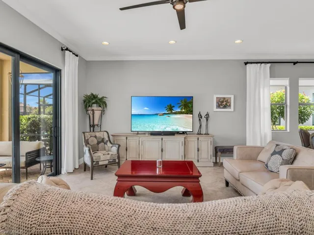 Tiled living room featuring ceiling fan, ornamental molding, and plenty of natural light