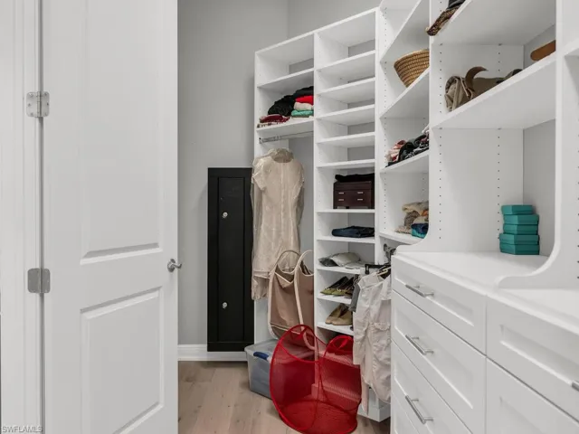 Walk in closet with light hardwood / wood-style floors