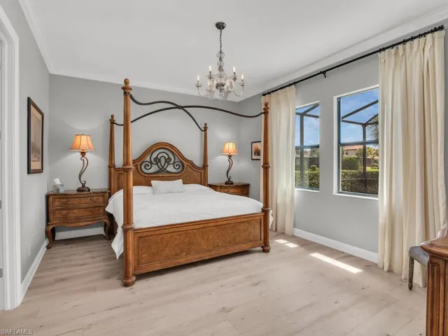 Bedroom featuring light hardwood / wood-style floors, ornamental molding, and a chandelier