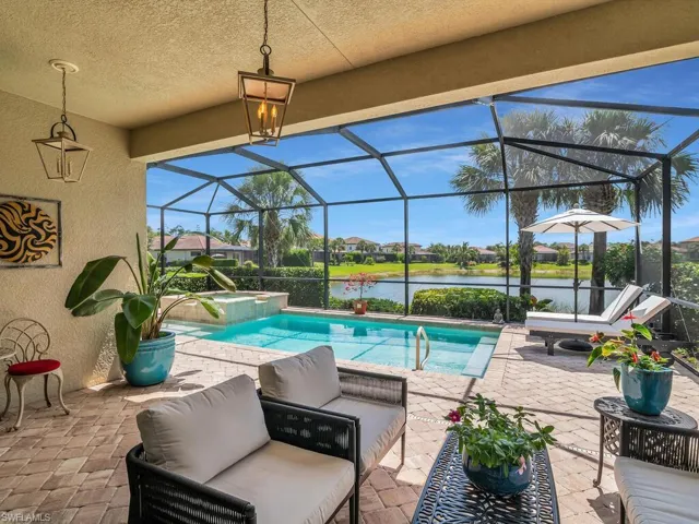 View of swimming pool featuring a water view, glass enclosure, an in ground hot tub, and a patio
