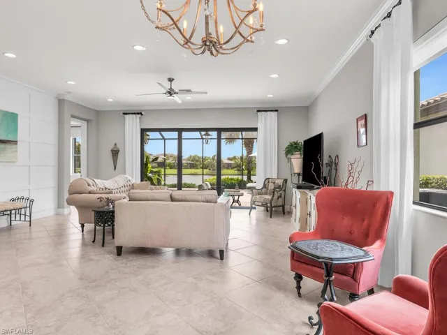 Tiled living room featuring ceiling fan with notable chandelier and ornamental molding