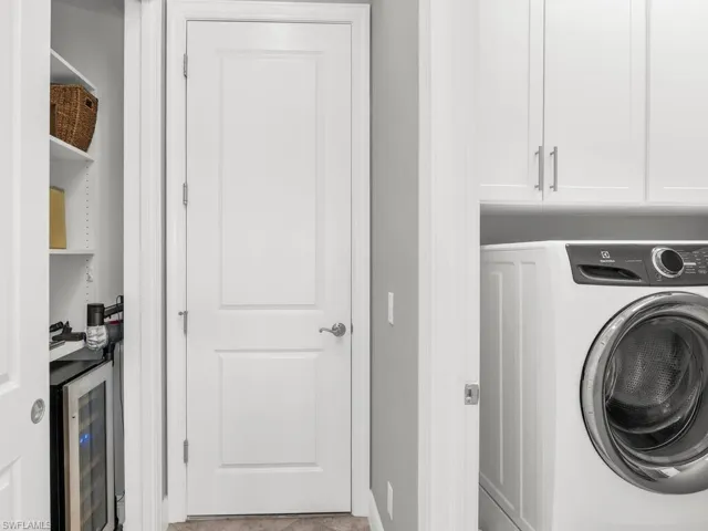 Washroom featuring cabinets, beverage cooler, and washer / clothes dryer