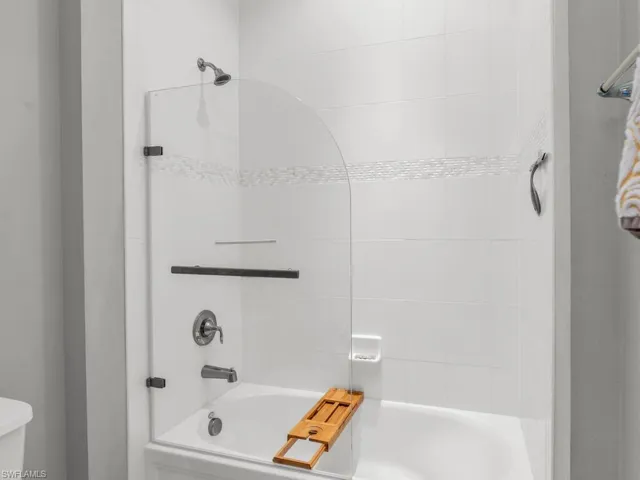 Bathroom with tiled shower / bath combo and toilet