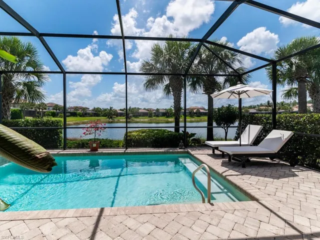 View of swimming pool featuring a patio, glass enclosure, and a water view