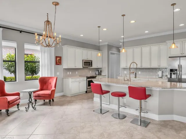 Kitchen featuring white cabinetry, decorative light fixtures, appliances with stainless steel finishes, and light stone countertops