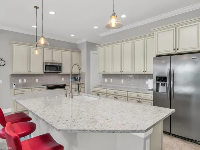 Kitchen featuring hanging light fixtures, stainless steel appliances, backsplash, and cream cabinetry