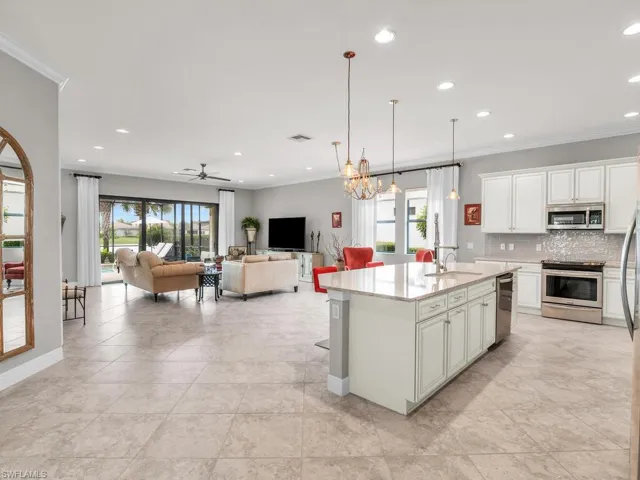 Kitchen featuring appliances with stainless steel finishes, decorative light fixtures, a healthy amount of sunlight, and a center island with sink