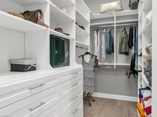 Walk in closet with light hardwood / wood-style flooring