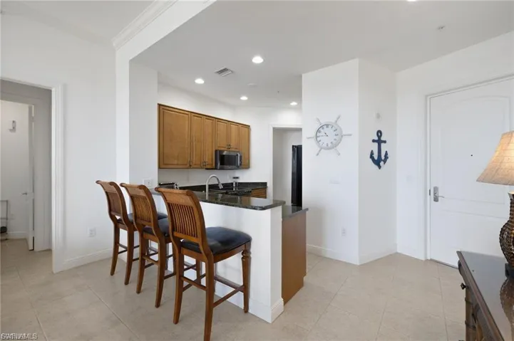 Kitchen with wood finish cabinets, a breakfast bar area, dark stone counters, a peninsula, and stainless steel microwave