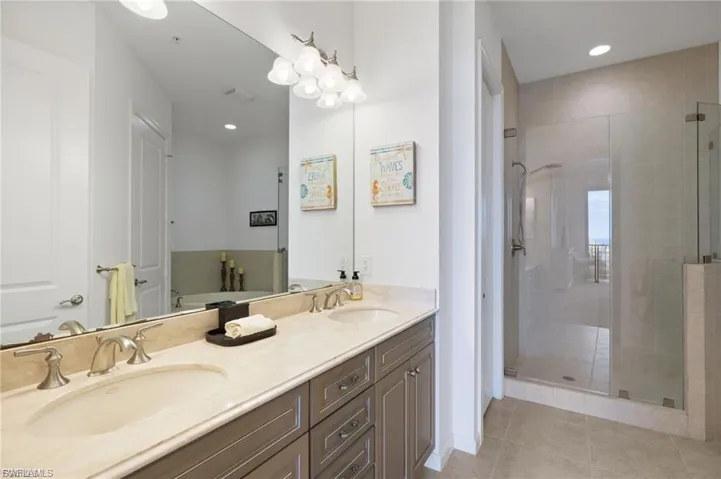 Full bath with double vanity, a stall shower, recessed lighting, and light tile patterned floors