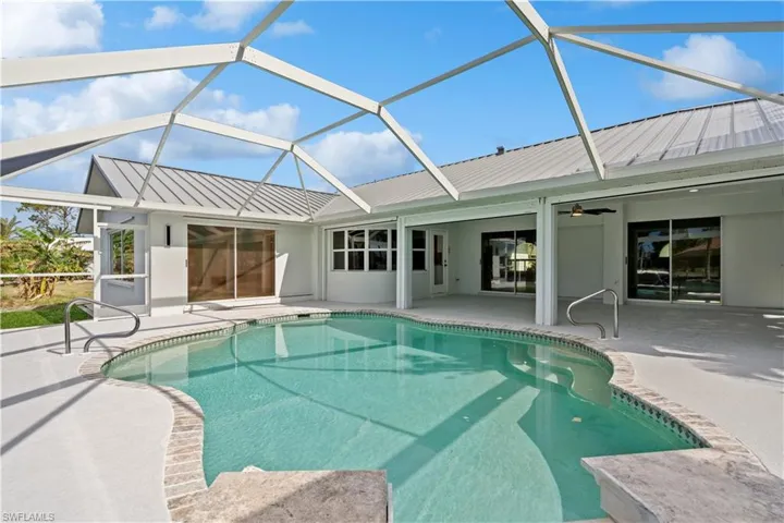 View of swimming pool featuring a jacuzzi, a patio, glass enclosure, and ceiling fan