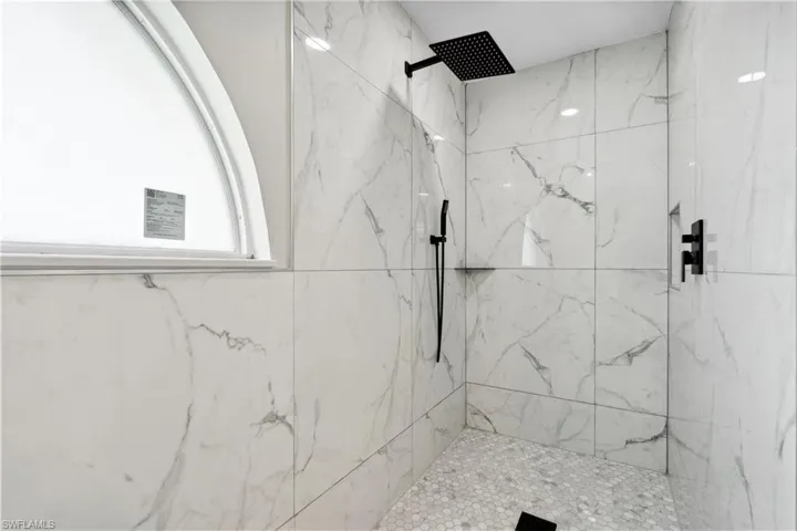 Bathroom with tile patterned floors, a washtub, vanity, and tile walls