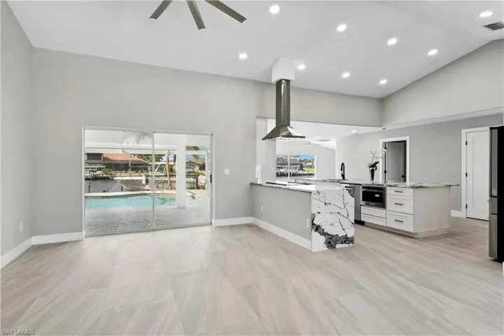 Kitchen with a large island, light stone counters, and white cabinetry
