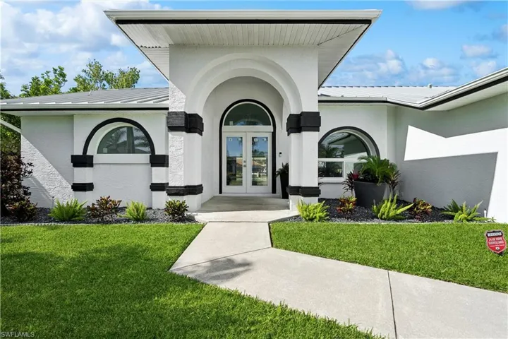 View of front of house with french doors, a garage, and a front lawn
