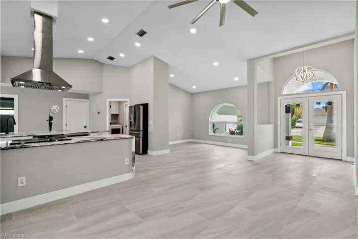 Kitchen featuring white cabinetry, ceiling fan, high vaulted ceiling, range hood, and kitchen peninsula