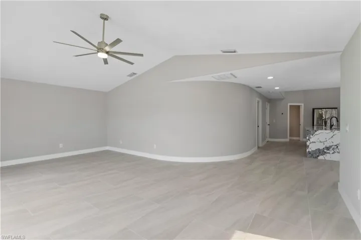 Unfurnished living room with ceiling fan, a water view, and lofted ceiling