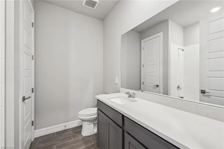 Bathroom with wood tiled floors, baseboards, toilet, and vanity