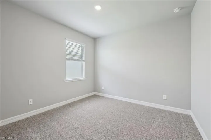 Empty room featuring carpet flooring, baseboards, recessed lighting, and a smoke detector