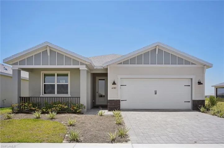 Craftsman inspired home with decorative driveway, a porch, an attached garage, board and batten siding, and stone siding
